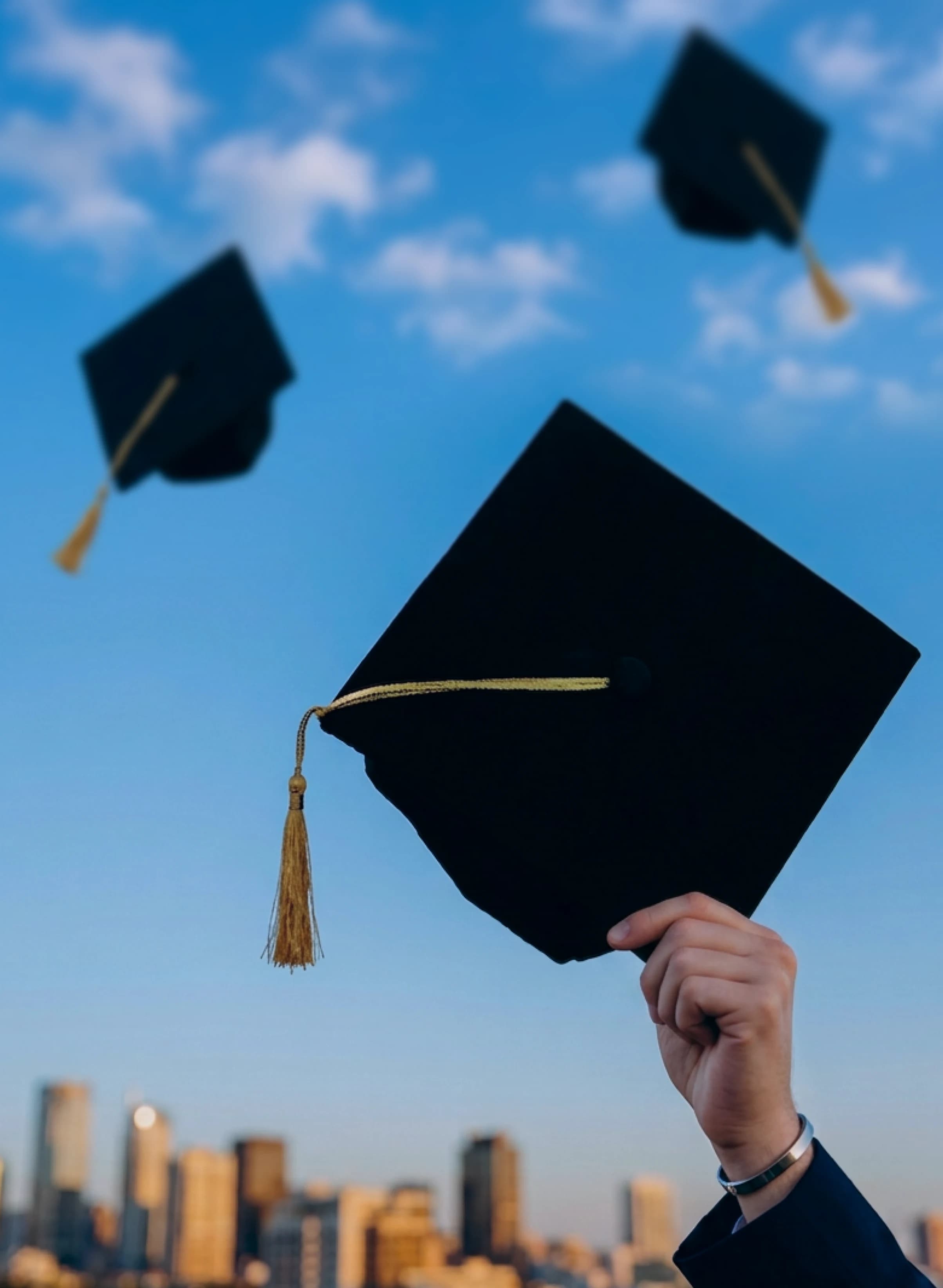 Graduation caps thrown in the air above a city skyline