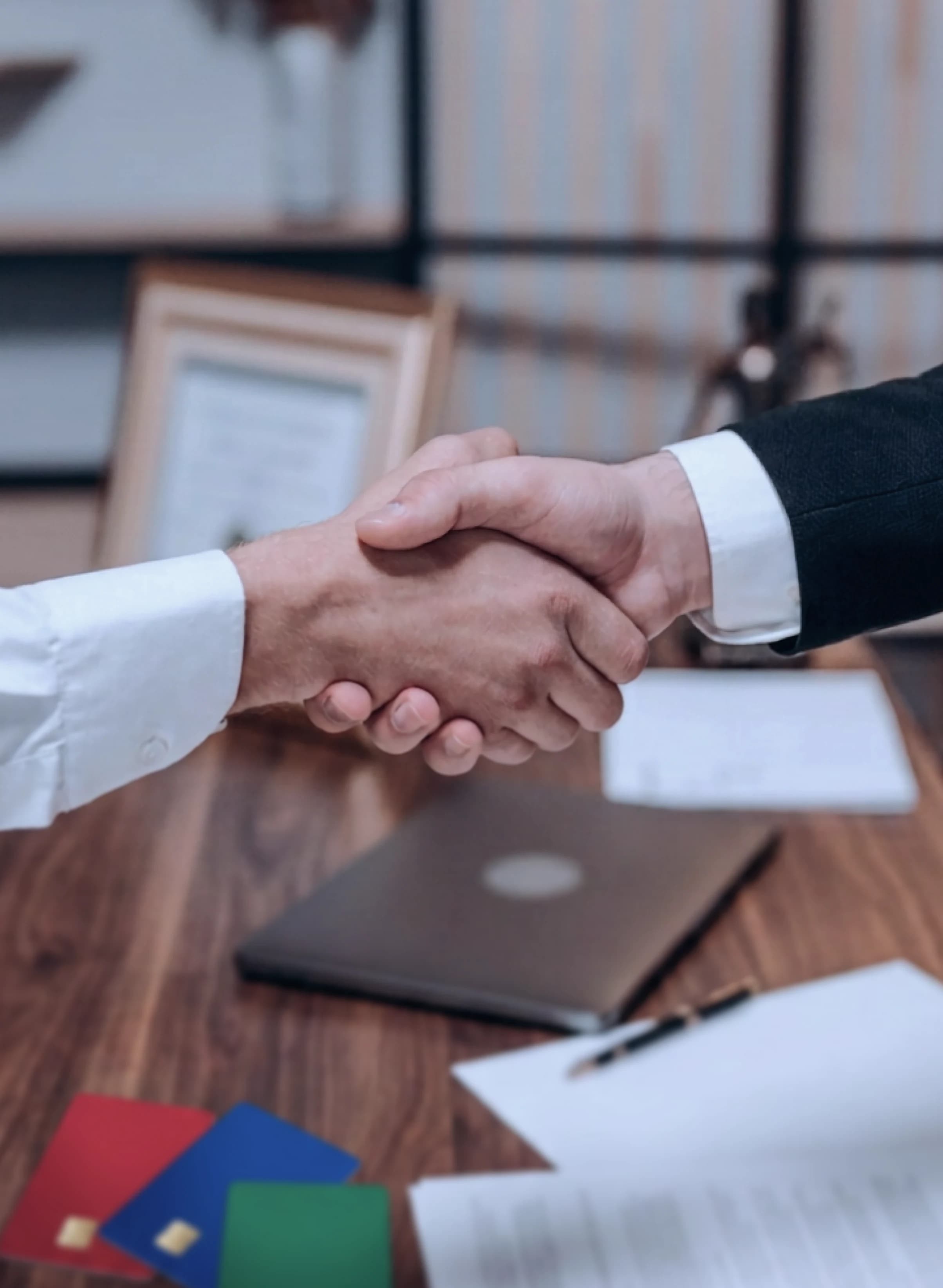 Business handshake over a desk with payment cards